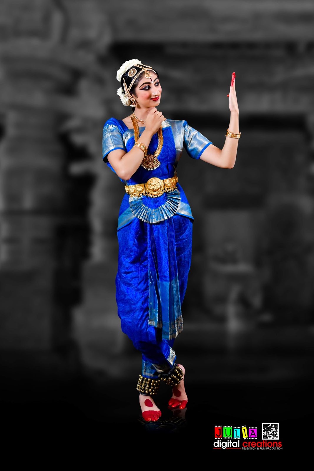 Arangetram dancer in a blue costume before a temple backdrop