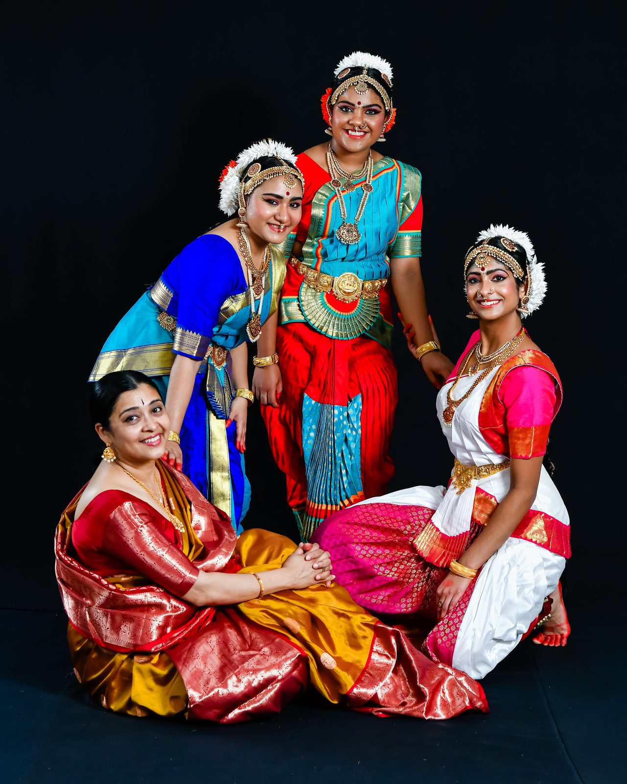 Dancers in classical costumes with a woman seated in a saree