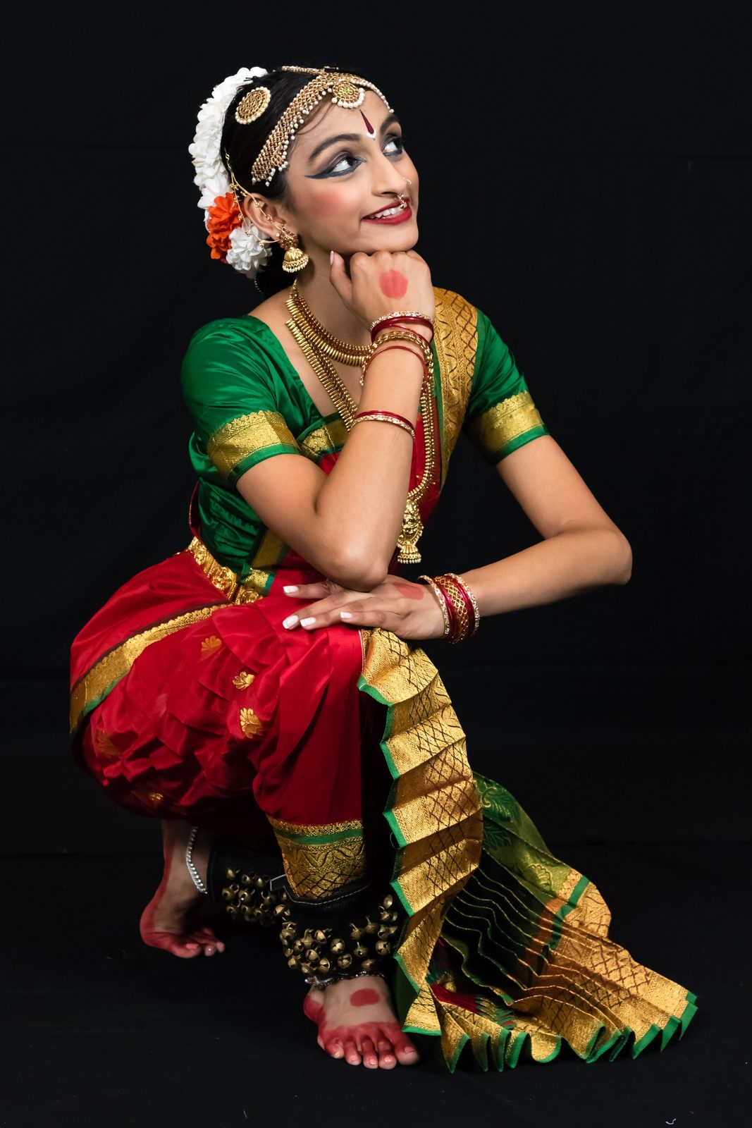 Arangetram dancer in red and green, kneeling pose