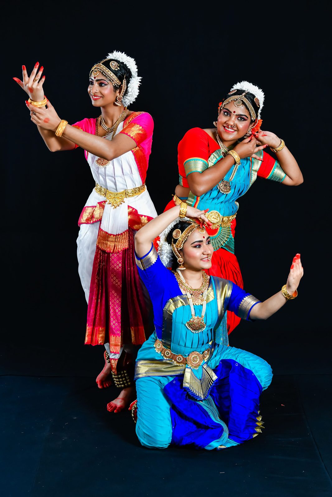 Three arangetram dancers in a layered pose