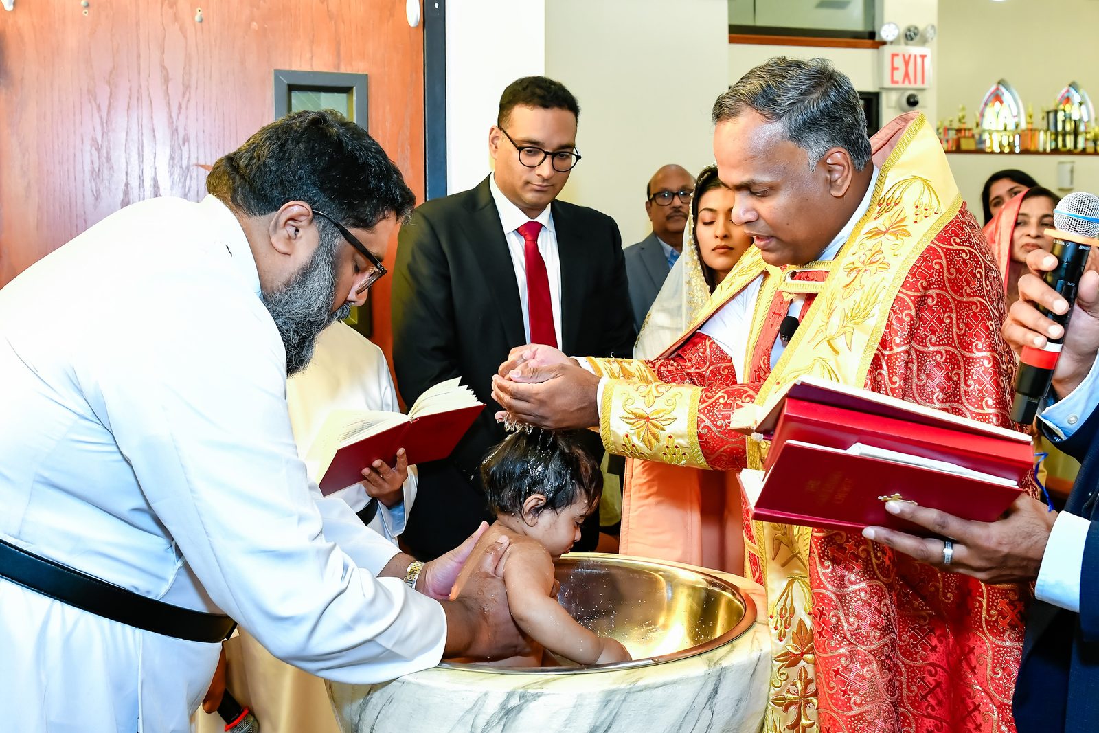 Priests baptizing a baby at the font