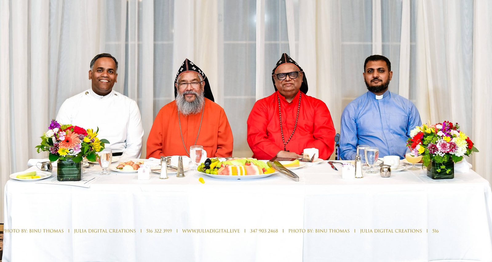 Clergy seated at a head table with flowers