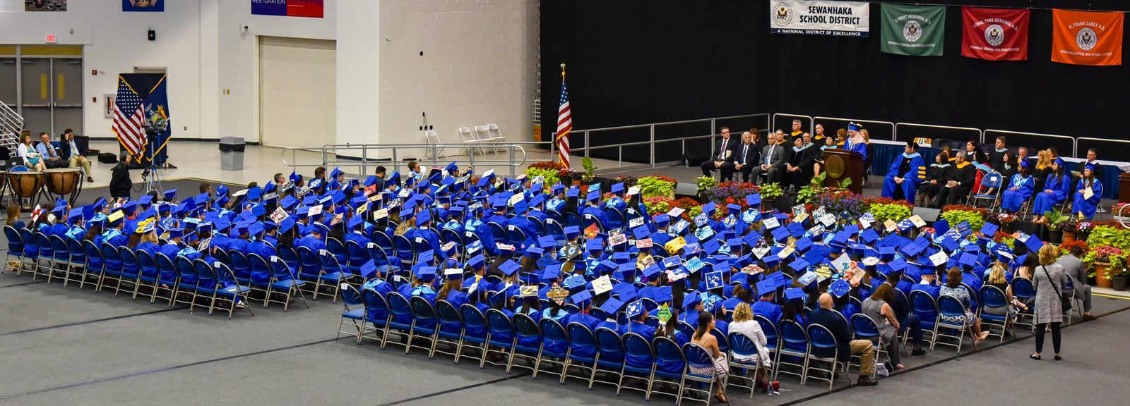 Graduates in blue gowns seated at a commencement ceremony