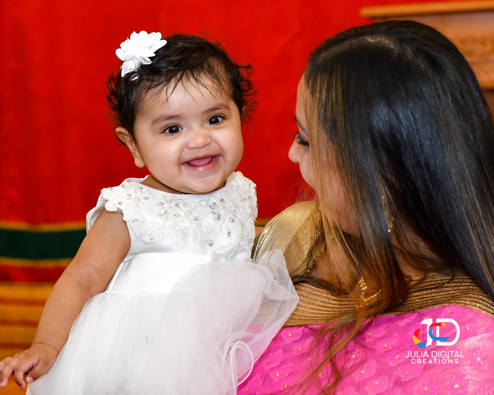 Smiling baby in a white dress with her mother at a baptism