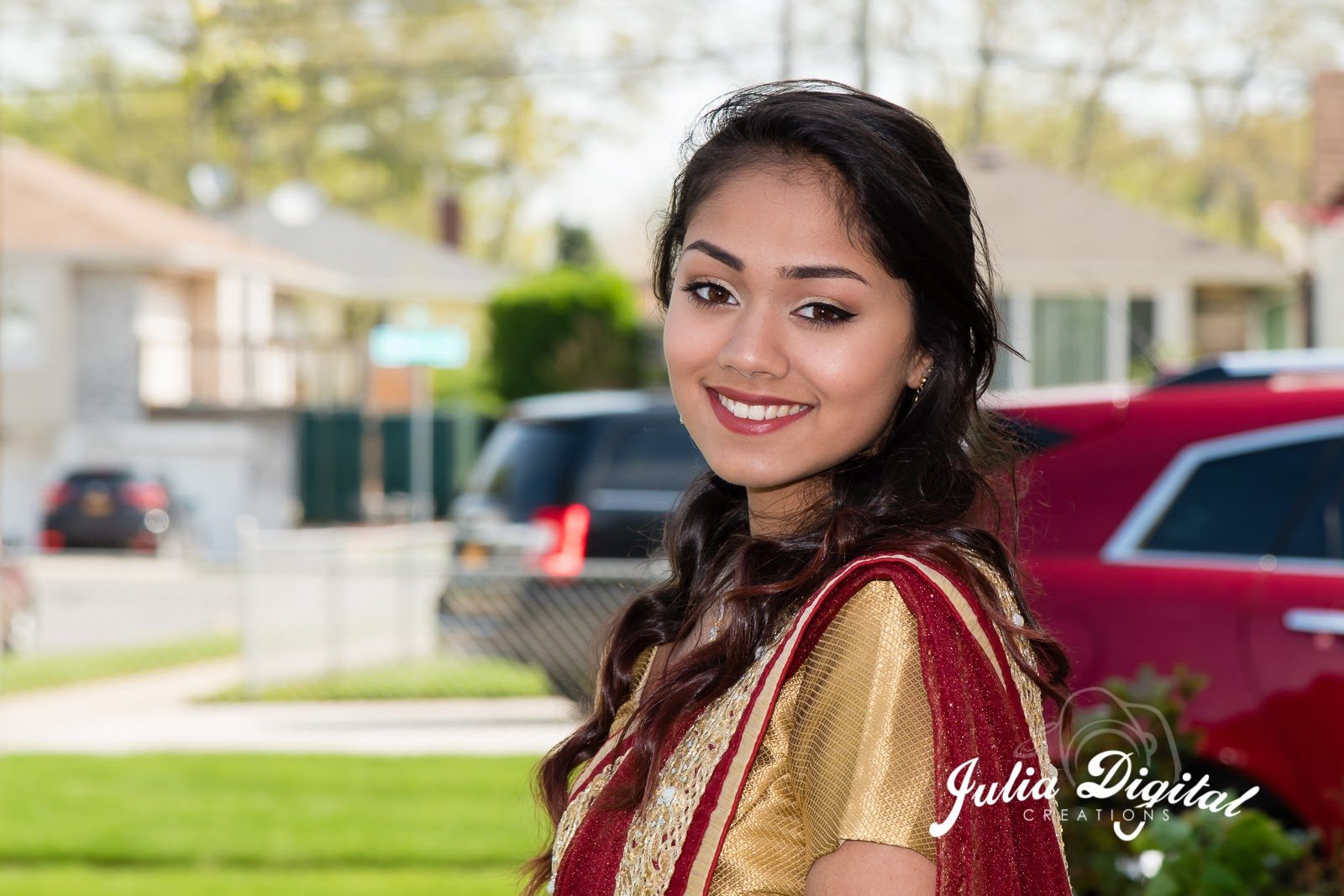 Smiling portrait in a red and gold saree outdoors