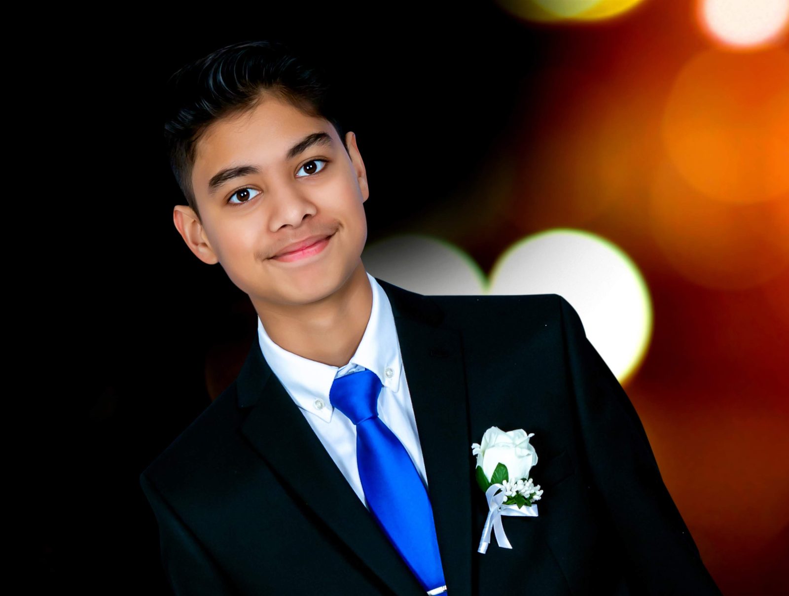 Portrait in a black suit with a blue tie and white boutonniere